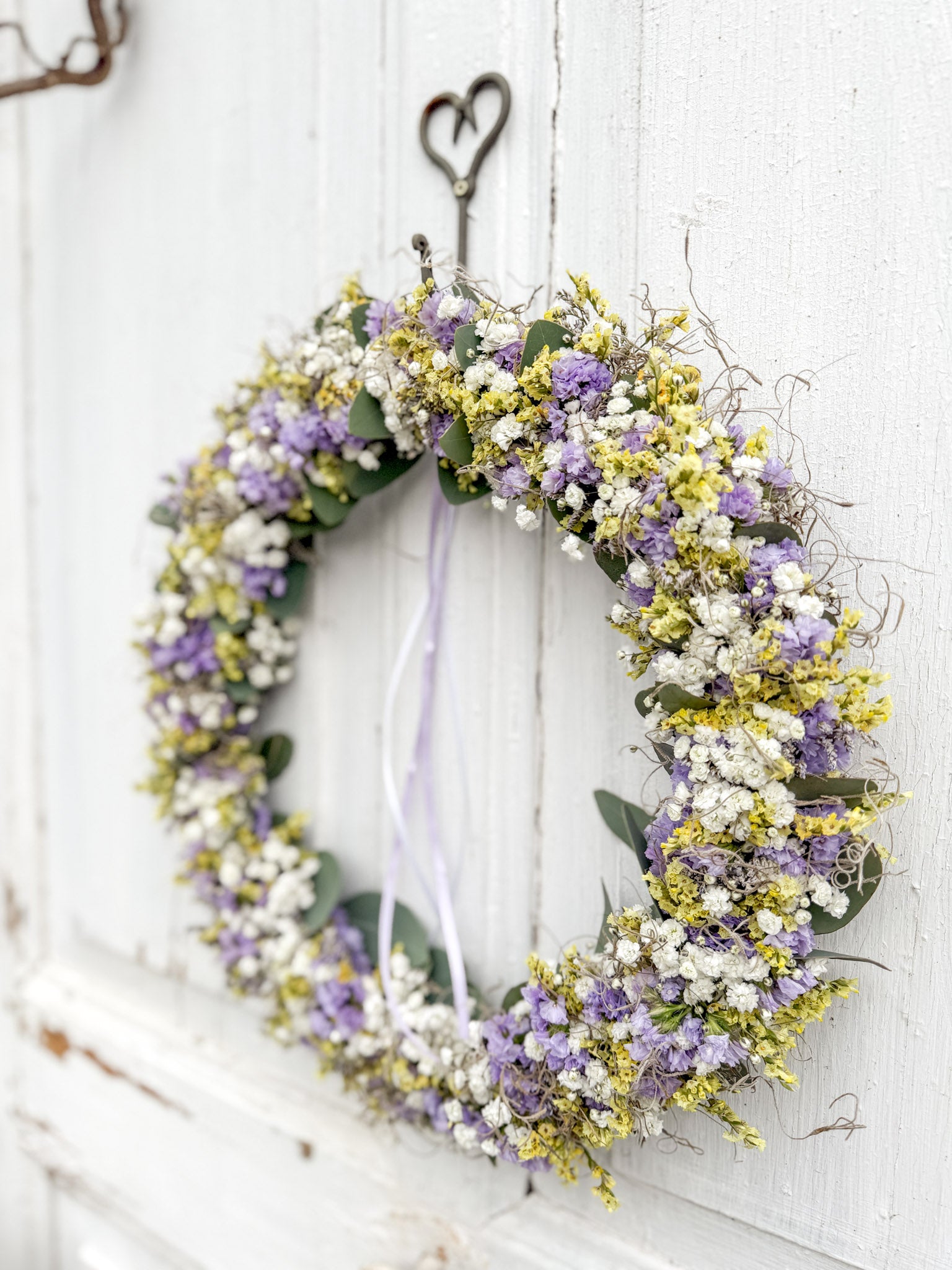 Handgefertigter FlowerLoop aus Eukalyptus mit Schleierkraut und Strandflieder in Flieder und Gelb + Tillandsia-Moos