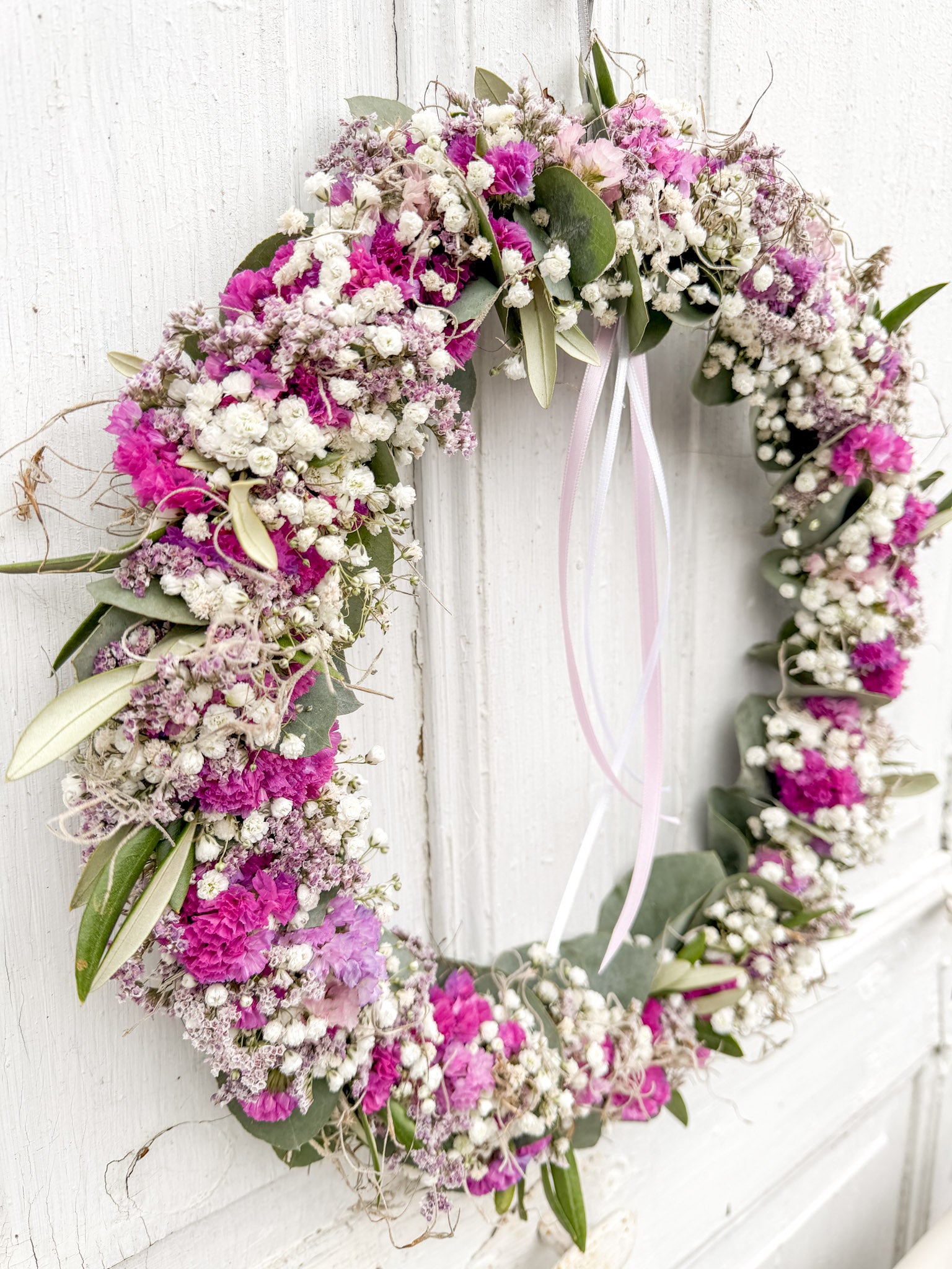 »1/1 FlowerLoop Rosa« vor weißer Wand – Eukalyptus, Schleierkraut, rosa Strandflieder und Tillandsia-Moos