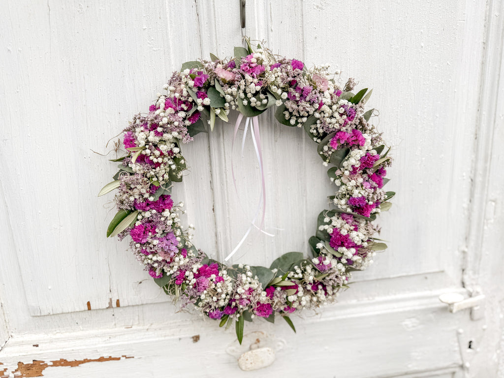 FlowerLoop Rosa quer an dunkler Tür – natürliche Wanddekoration mit Schleierkraut und Tillandsia-Moos