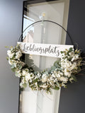 Moderner FlowerLoop mit weißen Blüten und Eukalyptus an dunkler Haustüre – Türkranz mit Schriftzug „Lieblingsplatz“.