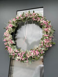 »1/1 FlowerLoop Rosa« vor an dunkler Haustüre – Eukalyptus, Schleierkraut, rosa Strandflieder und Tillandsia-Moos