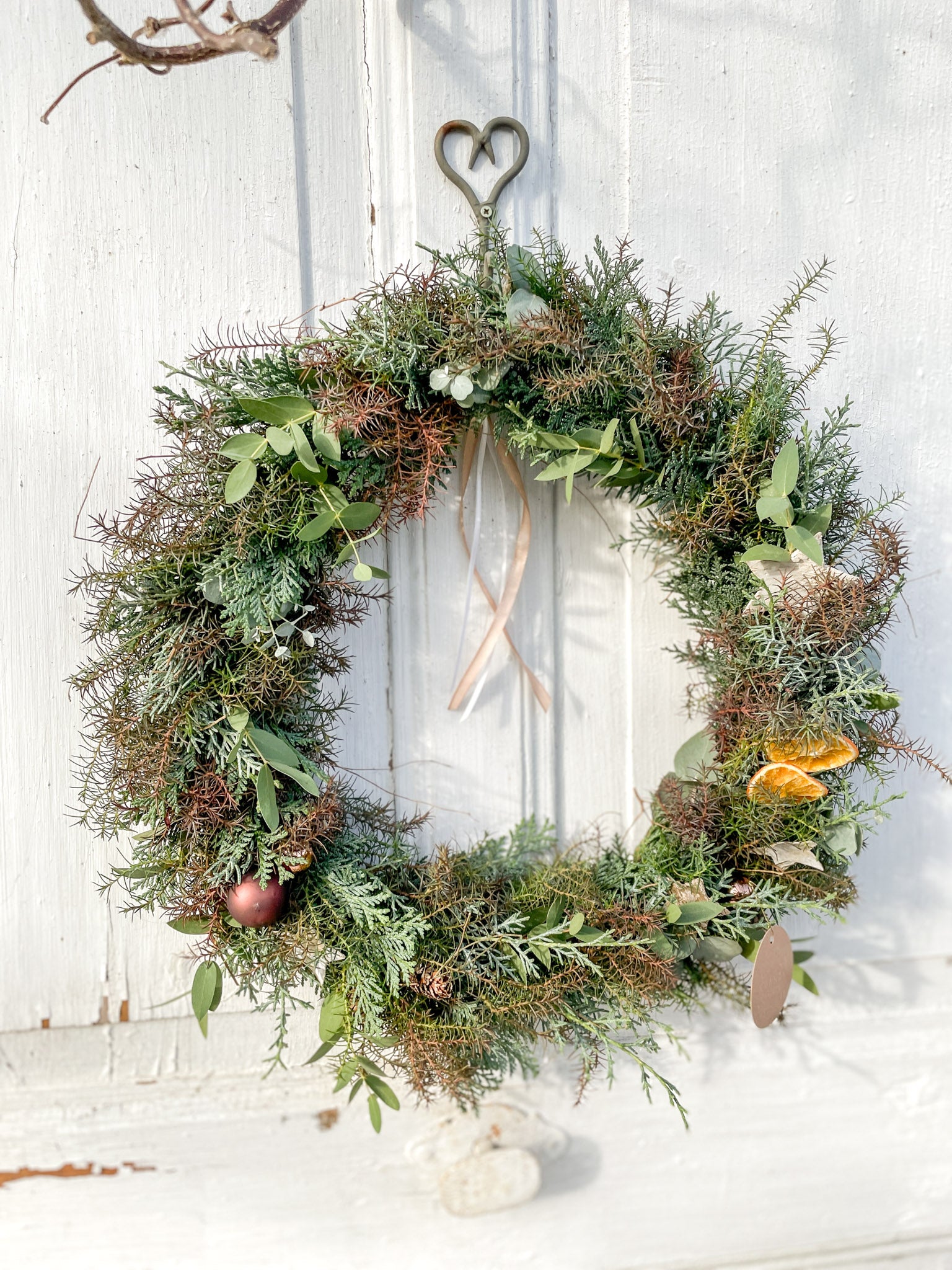 Winter Loop ‚Nordic Glow‘ auf Metallring, Eukalyptus und Koniferengrün in Blau- und Brauntönen mit Orangenscheiben, Birkensternen und Dekokugeln