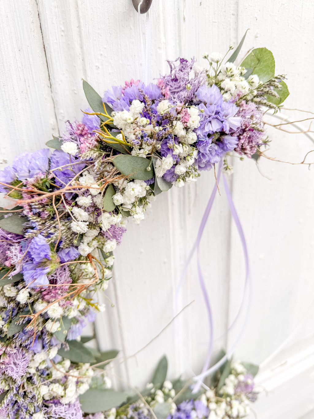 Detailaufnahme Flowerloop »Vertical Lila Spring«: lila Strandflieder, Limonium, weißes Schleierkraut, Islandmoos, Euphorbia spinosa und Satinband auf Metallring