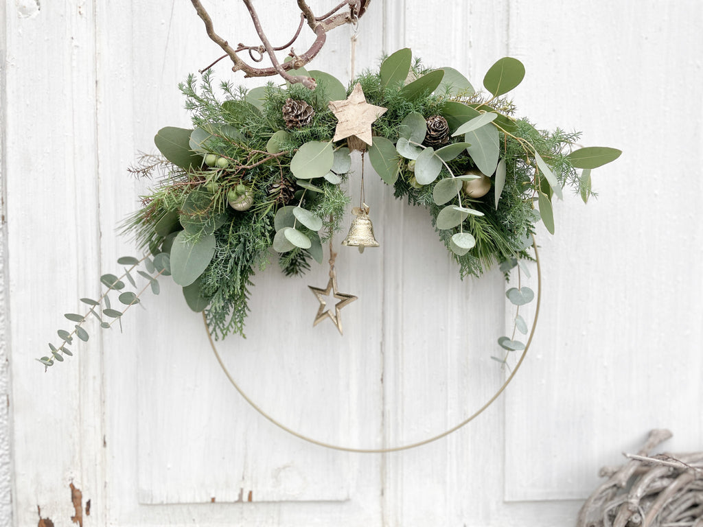 1/2 Winter-Loop ‚Evergreen Canopy‘ Querformat, Metallring halbseitig dekoriert mit Eukalyptus- und Koniferengrün, Zweige überragen oberen Rand, Lerchenzapfen, Birkensterne, Dekokugeln