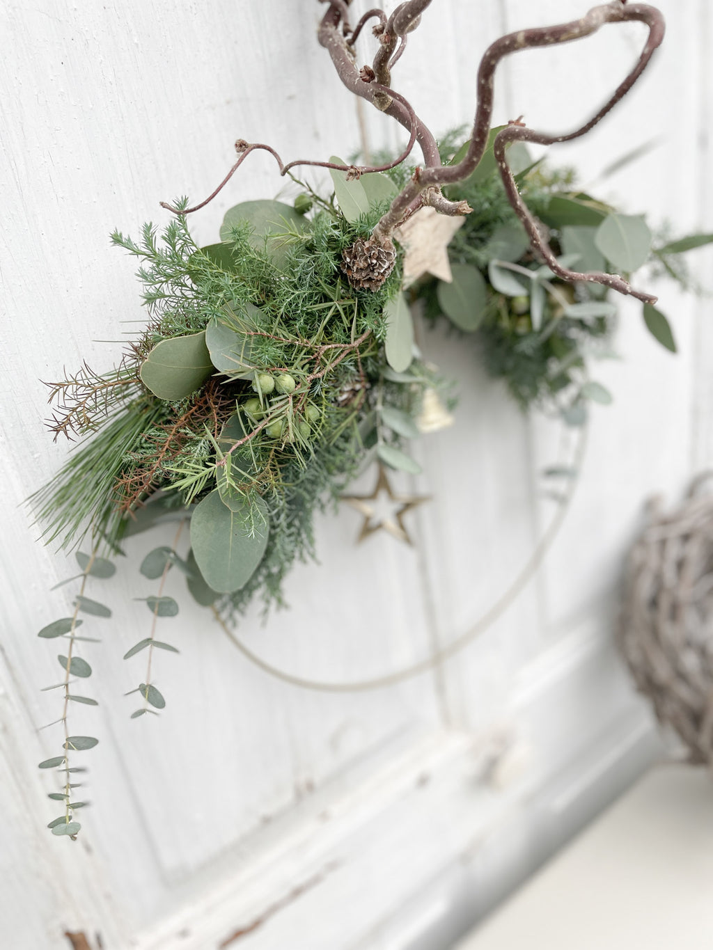 1/2 Winter-Loop ‚Evergreen Canopy‘ Hochformat, Ansicht von oben, Metallring halbseitig dekoriert mit Eukalyptus- und Koniferengrün, Zweige überragen oberen Rand, Lerchenzapfen, Birkensterne, Dekokugeln