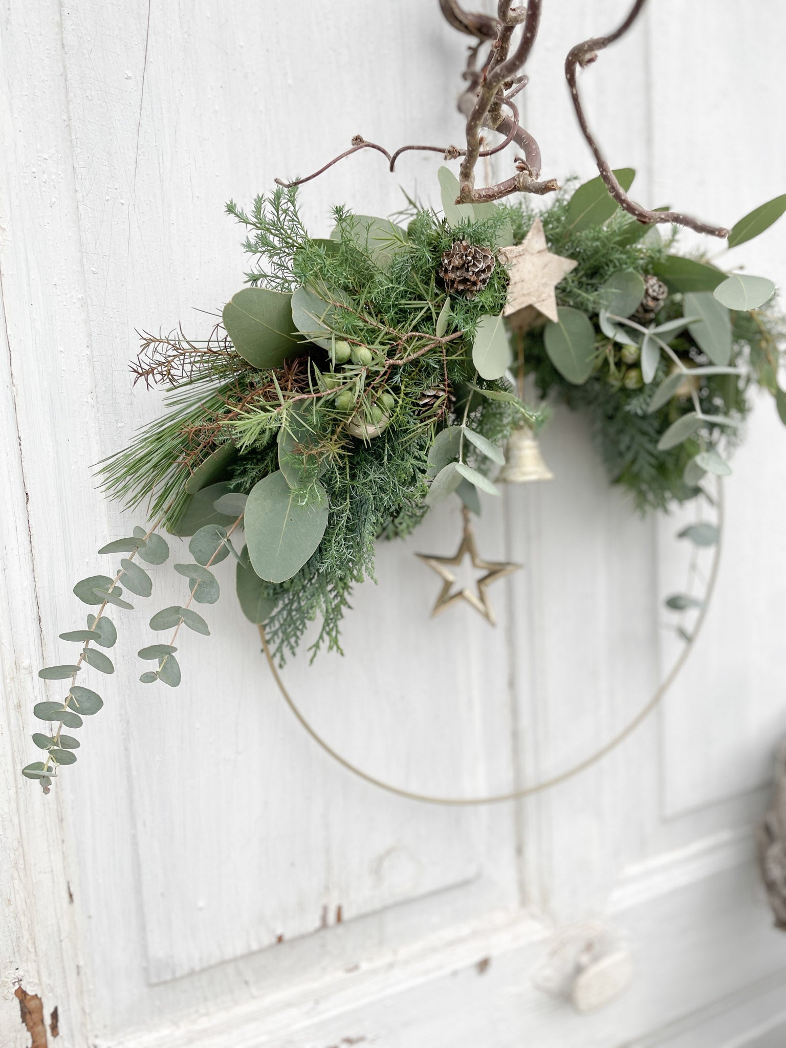 1/2 Winter-Loop ‚Evergreen Canopy‘ Hochformat, Metallring halbseitig dekoriert mit Eukalyptus- und Koniferengrün, Zweige überragen oberen Rand, Lerchenzapfen, Birkensterne, Dekokugeln