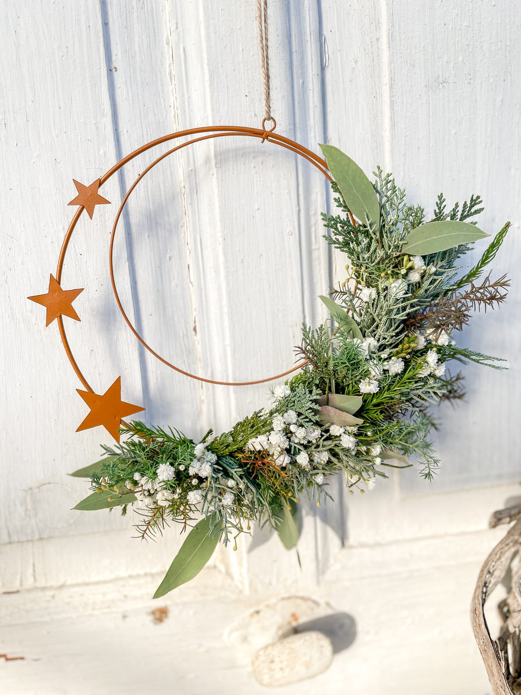 1/2 Winter-Loop ‚Rustic Stars‘ Hochformat, Metallring in Rostoptik mit zur Hälfte dekoriertem Koniferengrün, Thuja, Zypresse und weißem Schleierkraut, drei Sterne