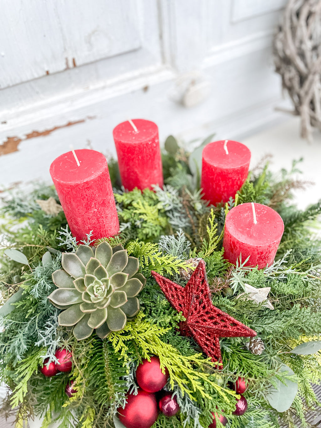 Detailansicht Adventskranz: Tanne, bläuliche Zypresse, Eukalyptus, rote Dekokugel und rotes Dekoelement