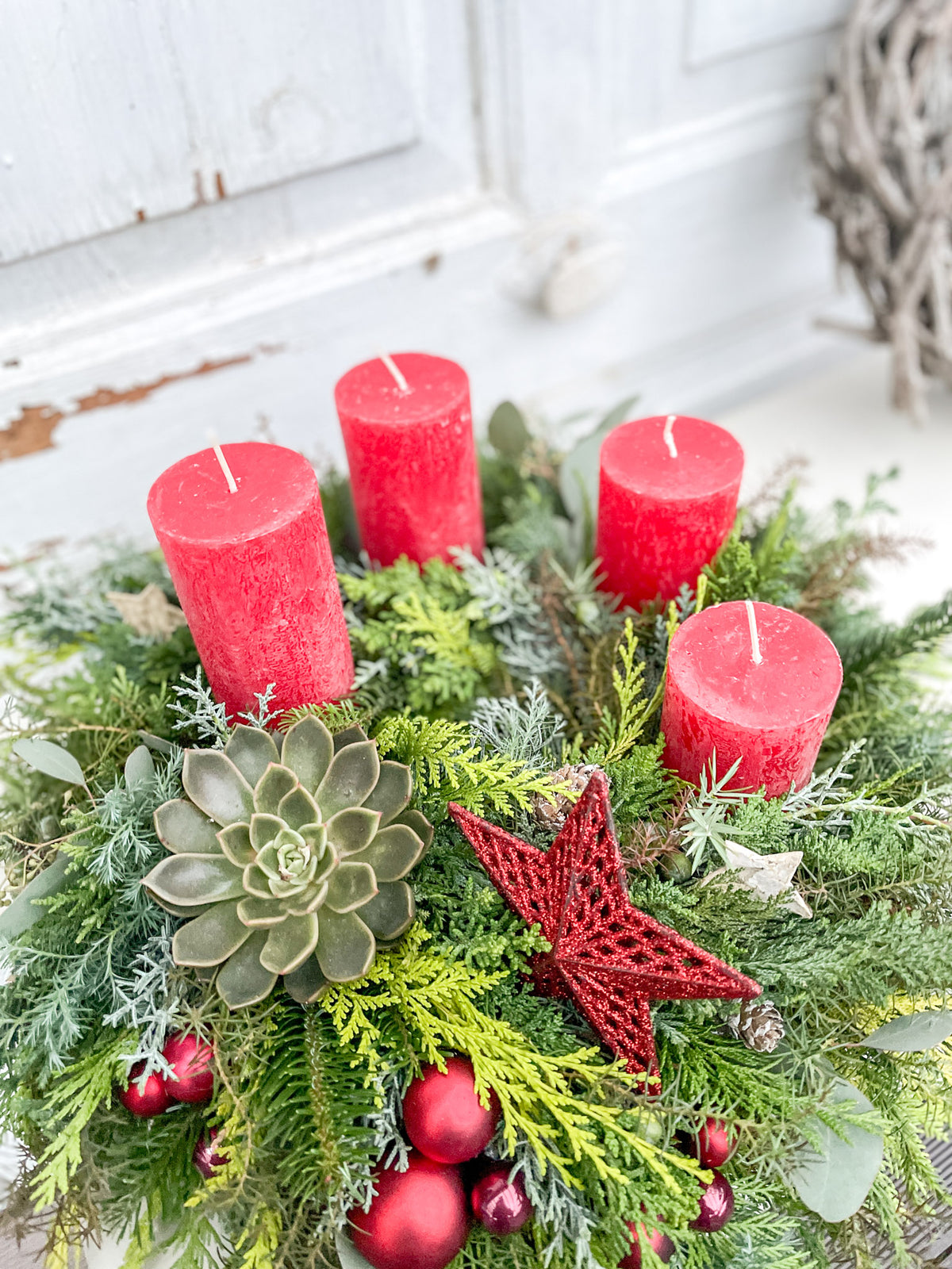 Detailansicht Adventskranz: Tanne, bläuliche Zypresse, Eukalyptus, rote Dekokugel und rotes Dekoelement