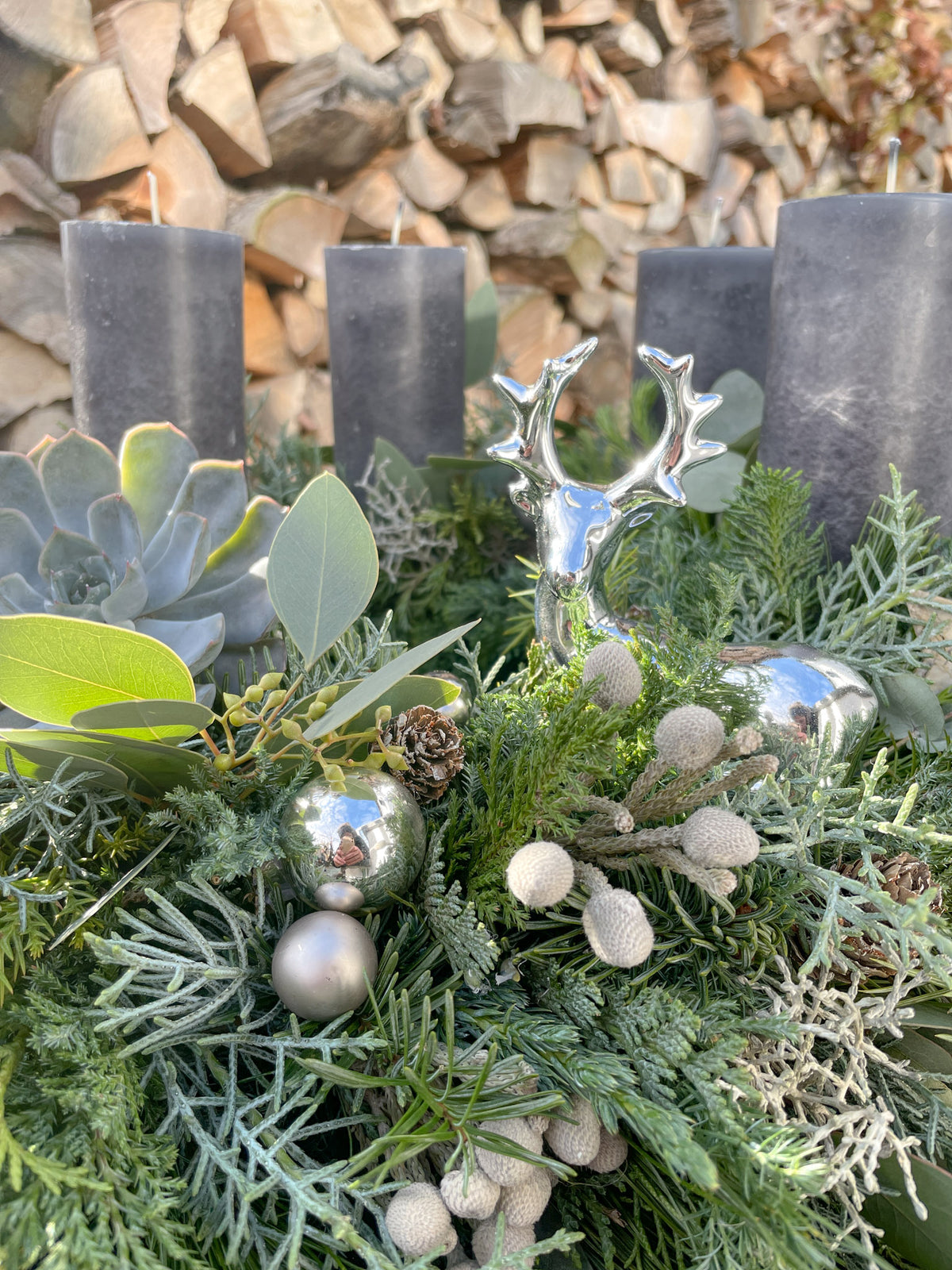 Detailansicht: Sukkulente, Eukalyptus und silbernes Dekoelement im Nadelgrün des Adventskranzes