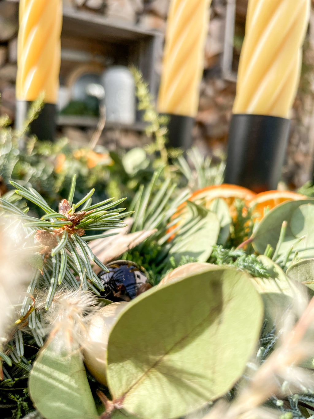 Detailansicht: getrocknete Orangenscheibe, Birkenstern und goldene Dekokugel im Nadelgrün des Adventskranzes