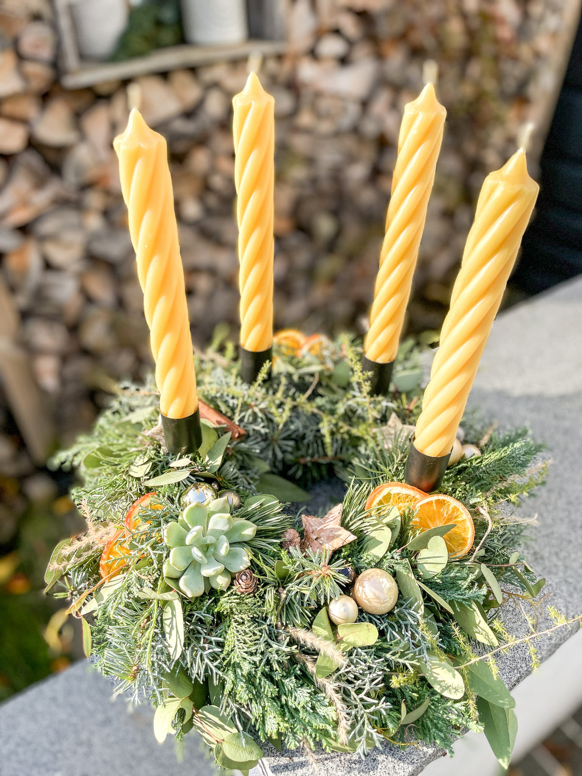 Ansicht leicht von oben: Adventskranz »Honigzimt-Twist« mit Pampasgras, Eukalyptus und champagnergoldenen Kugeln vor Holzwand