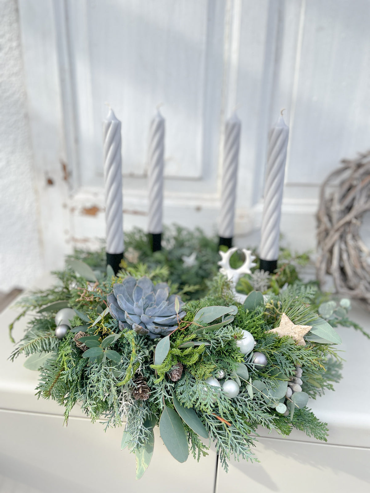 Skandi-Deko Adventskranz »Nebelhirsch-Twist« mit grauen Stabkerzen, Nadelgrün und Eukalyptus vor heller Holzwand