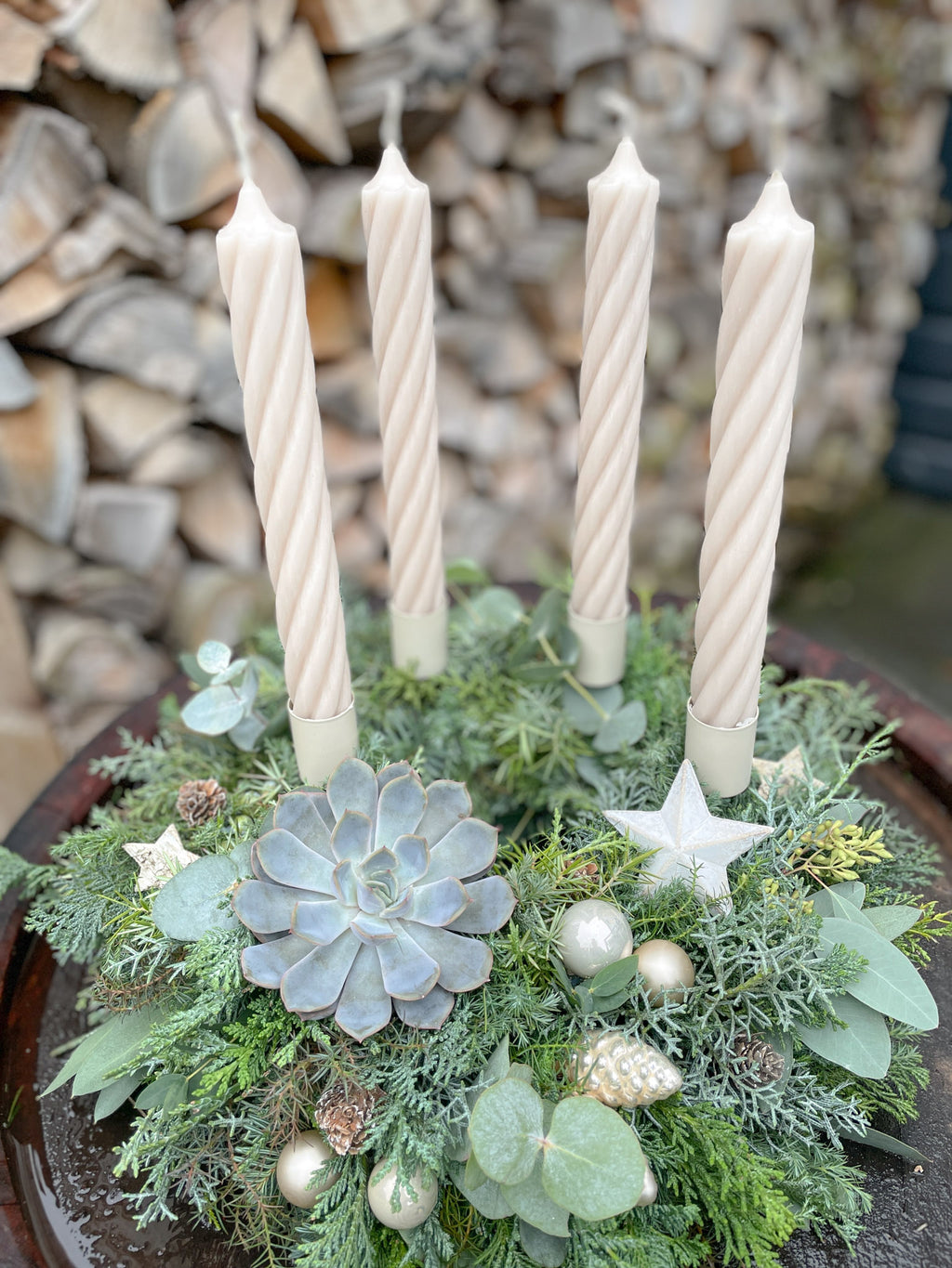 Adventskranz »Sandhauch-Twist« auf Holzfass mit beigen Stabkerzen, champagnerfarbenen Kugeln und geweißelten Zapfen