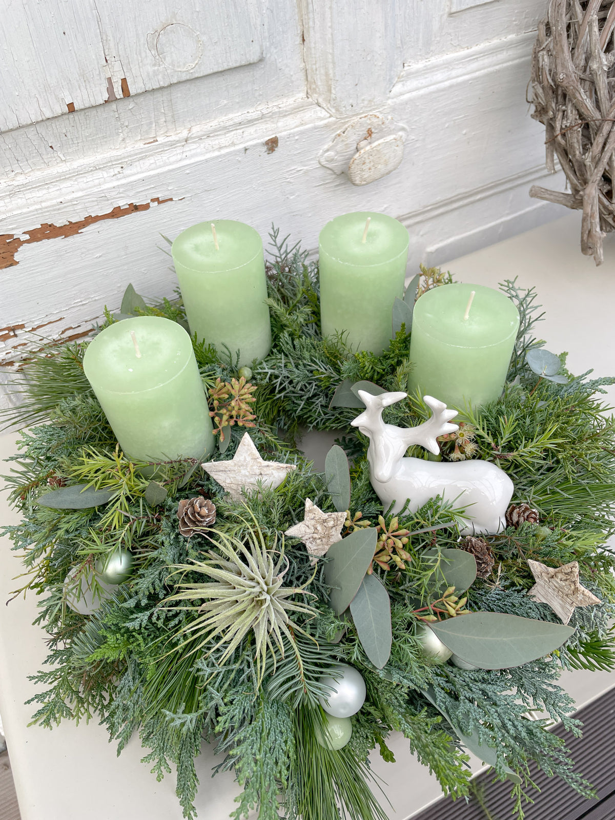 Draufsicht auf den Adventskranz »Waldhirsch« mit Luftpflanze, Nadelgrün, Zapfen und weiß-grünen Dekokugeln
