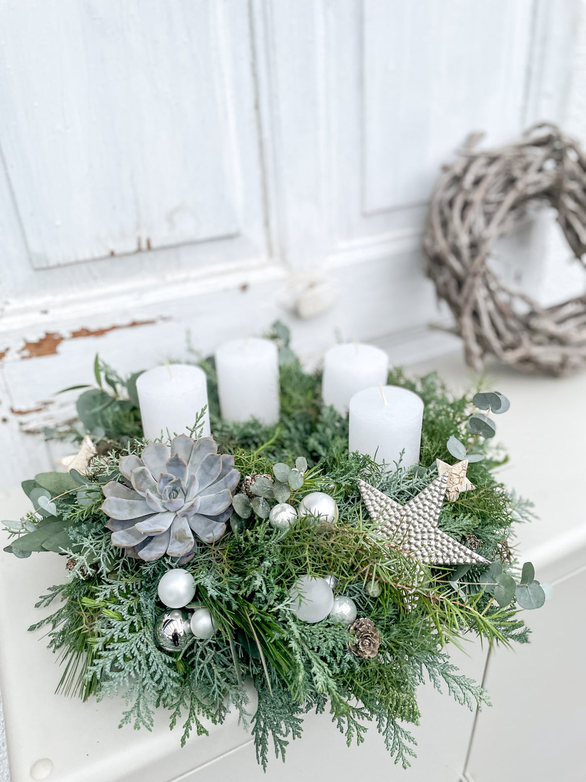 Adventskranz »Winterlicht« mit brennenden weißen Kerzen vor heller Wand