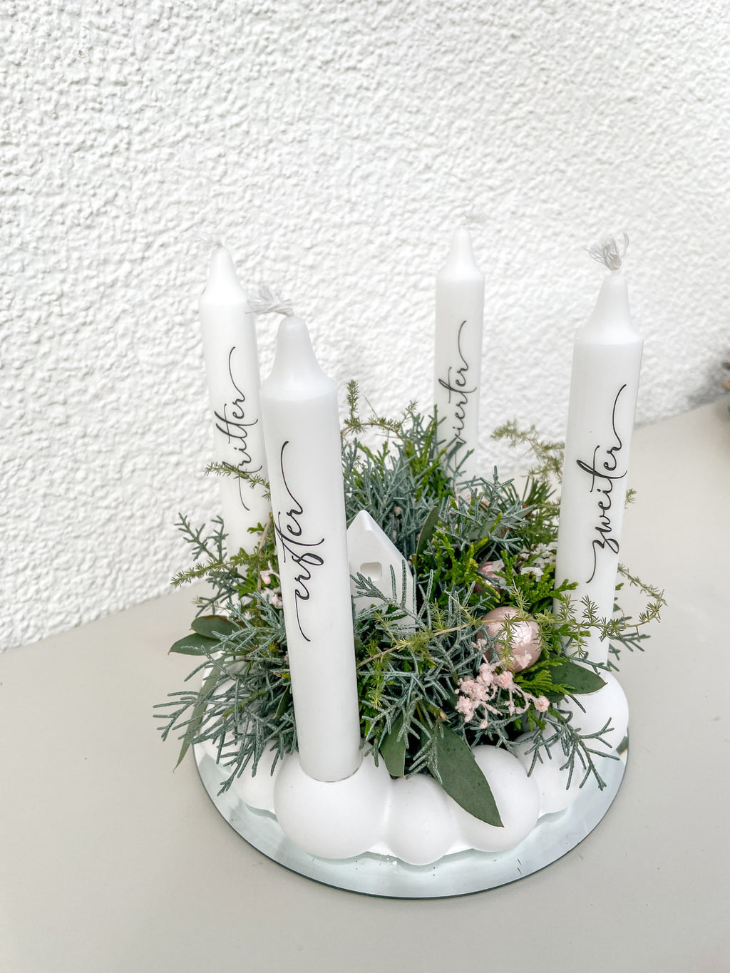 Vier weiße Stabkerzen mit Aufschriften „Erster“, „Zweiter“, „Dritter“, „Vierter“ auf Raysin-Kugelkranz