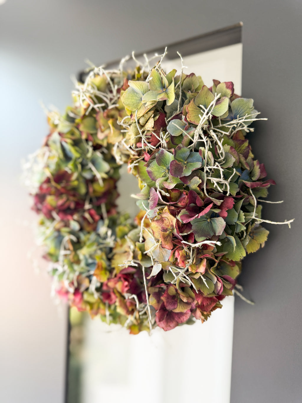 Herbstkranz aus französischer Hortensie und Stacheldraht an dunkler Haustüre