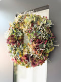 Herbstkranz aus französischer Hortensie und Stacheldraht an dunkler Haustüre
