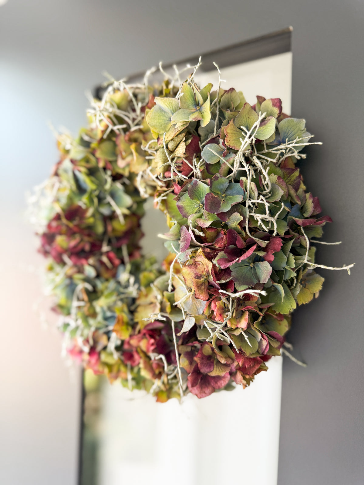 Herbstkranz aus französischer Hortensie und Stacheldraht an dunkler Haustüre