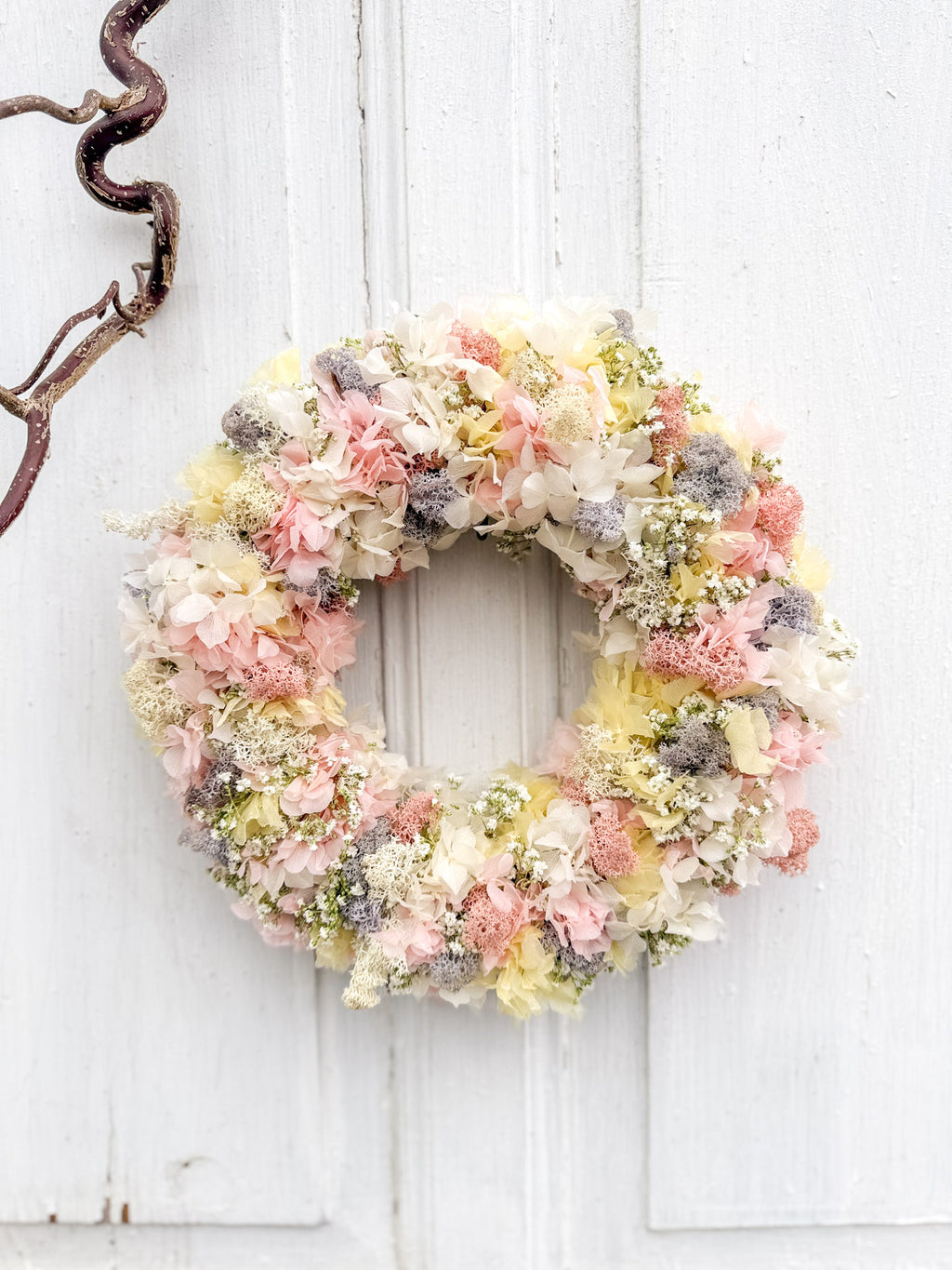 Frühlings-Blumenkranz »Pastell Bloom« aus stabilisierten Hortensien in Rosé, Gelb und Weiß, kombiniert mit Islandmoos und weißem Schleierkraut, frontal