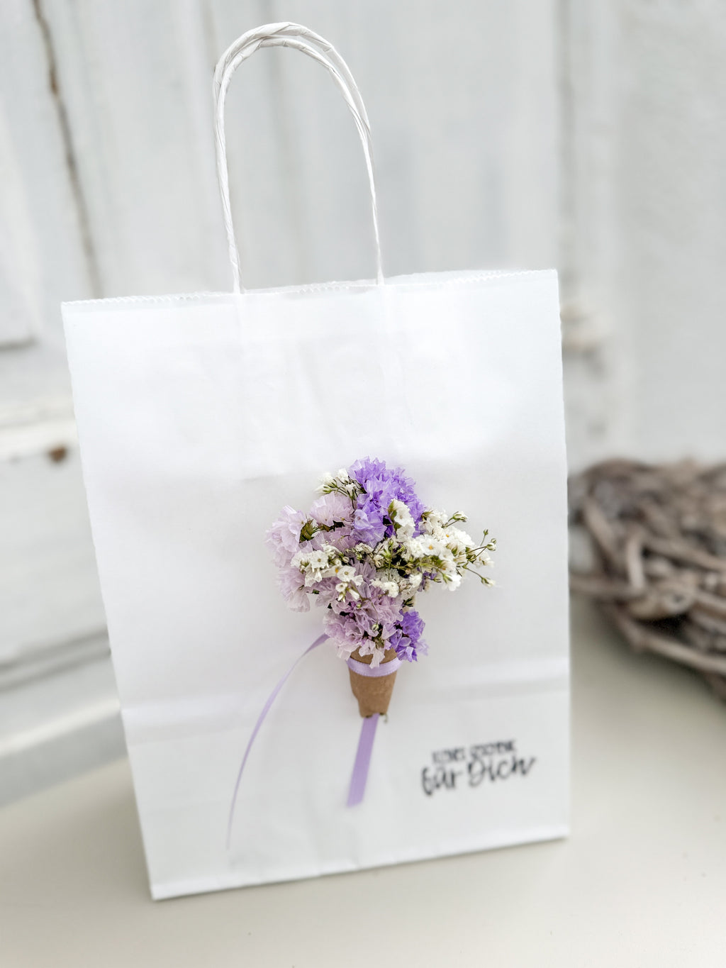 Weiße Geschenktüte mit lila Mini-Bouquet