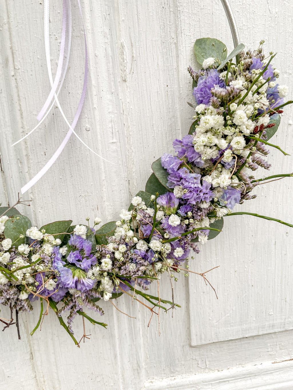 Detailaufnahme 1/2 Loop „Soft Seasons“ in Lila: lila Strandflieder, Statice, Limonium, Eukalyptus, Schleierkraut und Euphorbia spinosa auf Metallring, winterlich-frühlingshafte Dekoration