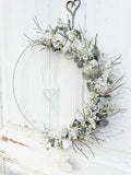 1/2 Loop »Vertical Winterwhite«, vertikal gebundener Metallring mit Eukalyptus, Heidelbeergrün, Schleierkraut und weißen Winterblüten, Satinbänder und hängendes Metallherz