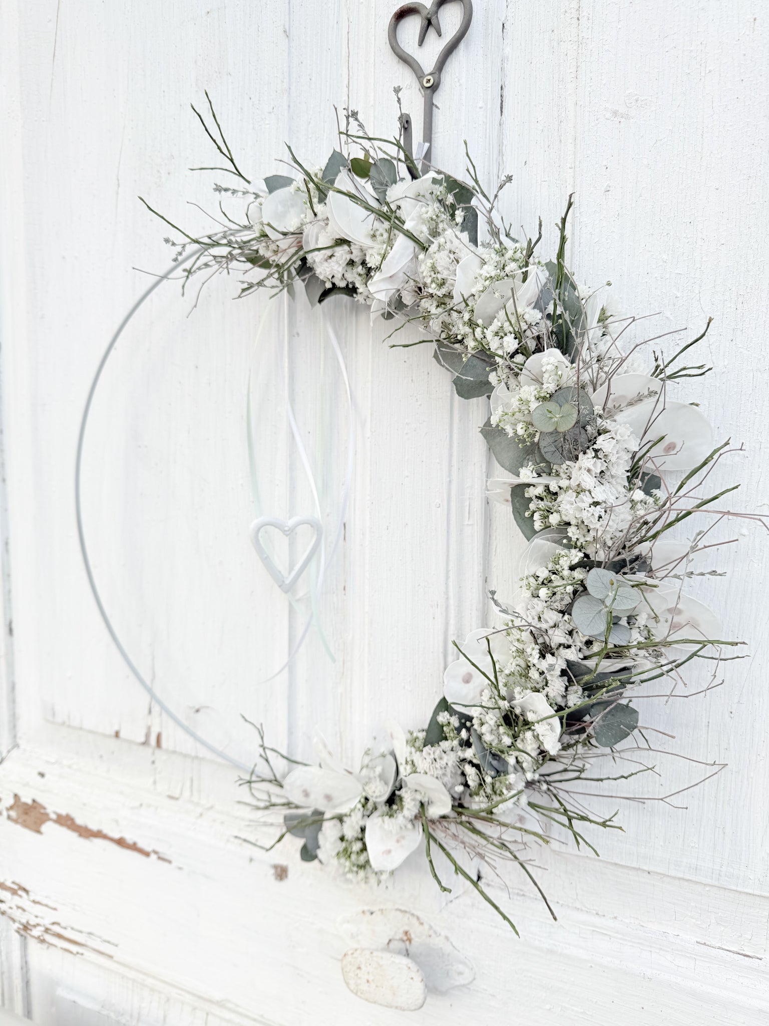 1/2 Loop »Vertical Winterwhite«, vertikal gebundener Metallring mit Eukalyptus, Heidelbeergrün, Schleierkraut und weißen Winterblüten, Satinbänder und hängendes Metallherz