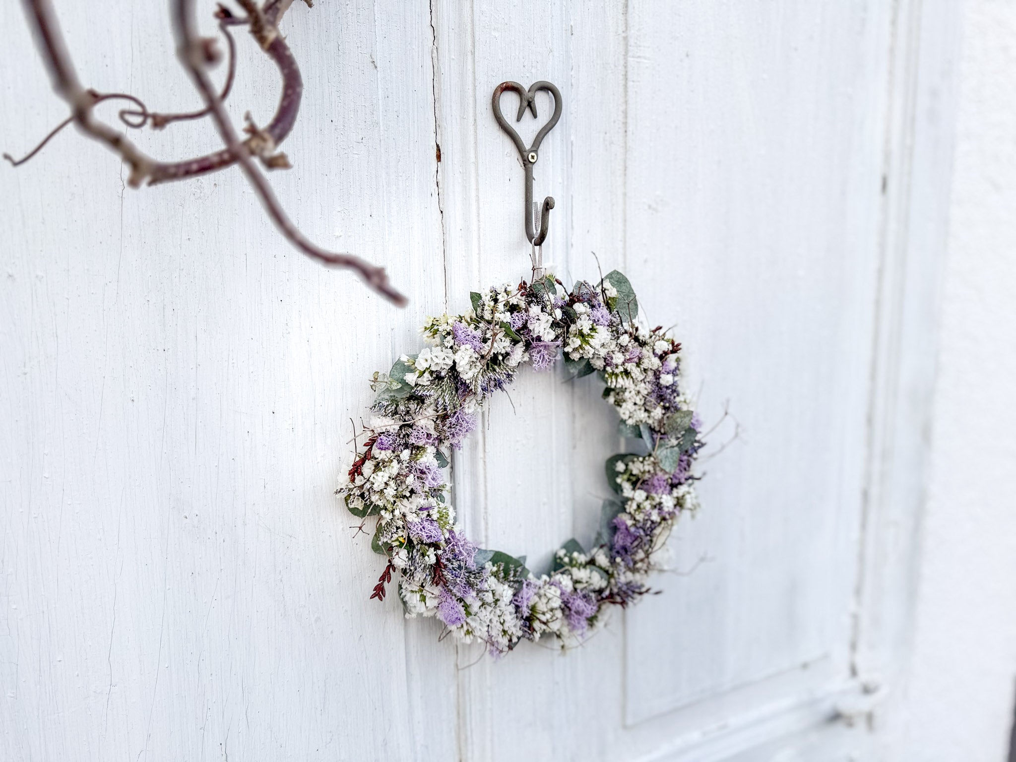 Voll gebundener Flowerloop aus Eukalyptus und weißen Blüten mit lila Highlights, ruhige und zeitlose Wanddekoration