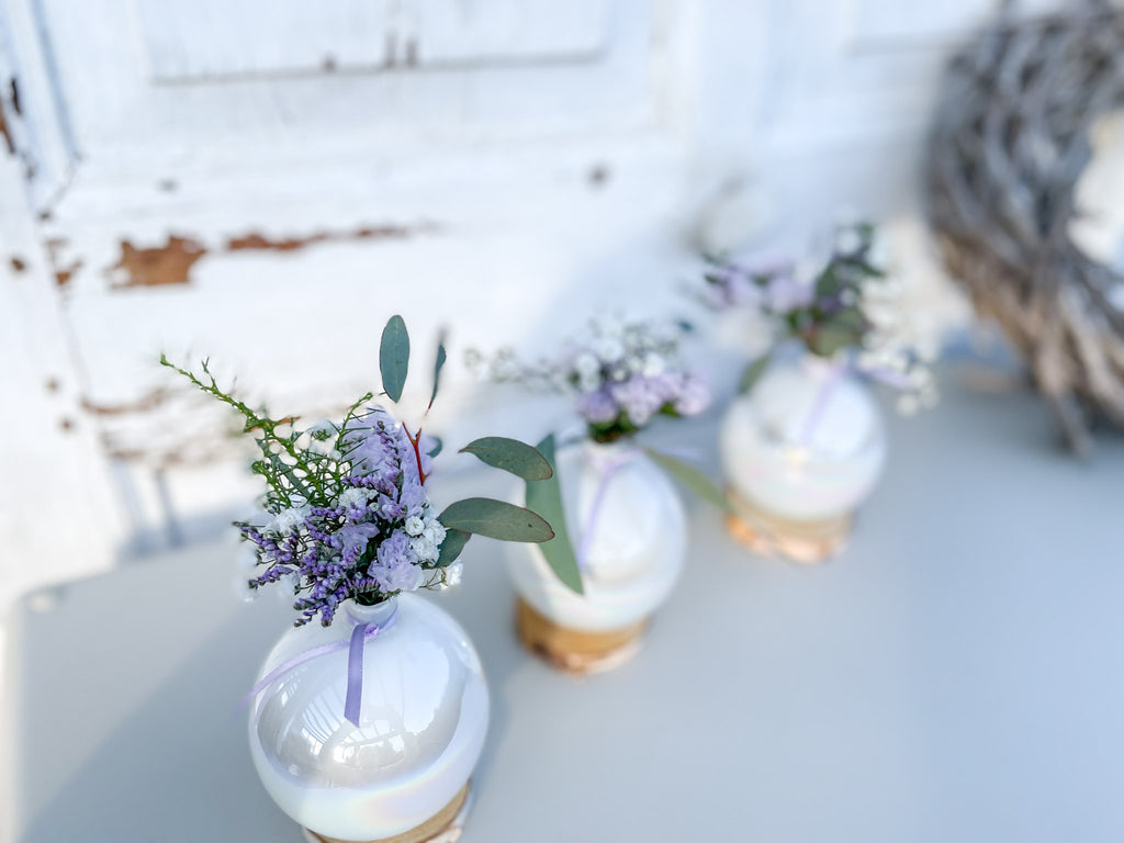 Christbaumkugel-Vase ‚Lila Blütenzauber‘ Querformat, Glasvase mit Perlmutschimmer auf Holzscheibe, dekorativ auf Tisch arrangiert mit lila Mini-Bouquet