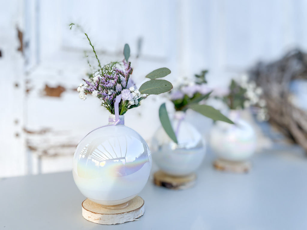 Detailaufnahme Christbaumkugel-Vase ‚Lila Blütenzauber‘ Querformat, Glasvase mit Perlmutschimmer auf Holzscheibe, dekorativ auf Tisch arrangiert mit lila Mini-Bouquet