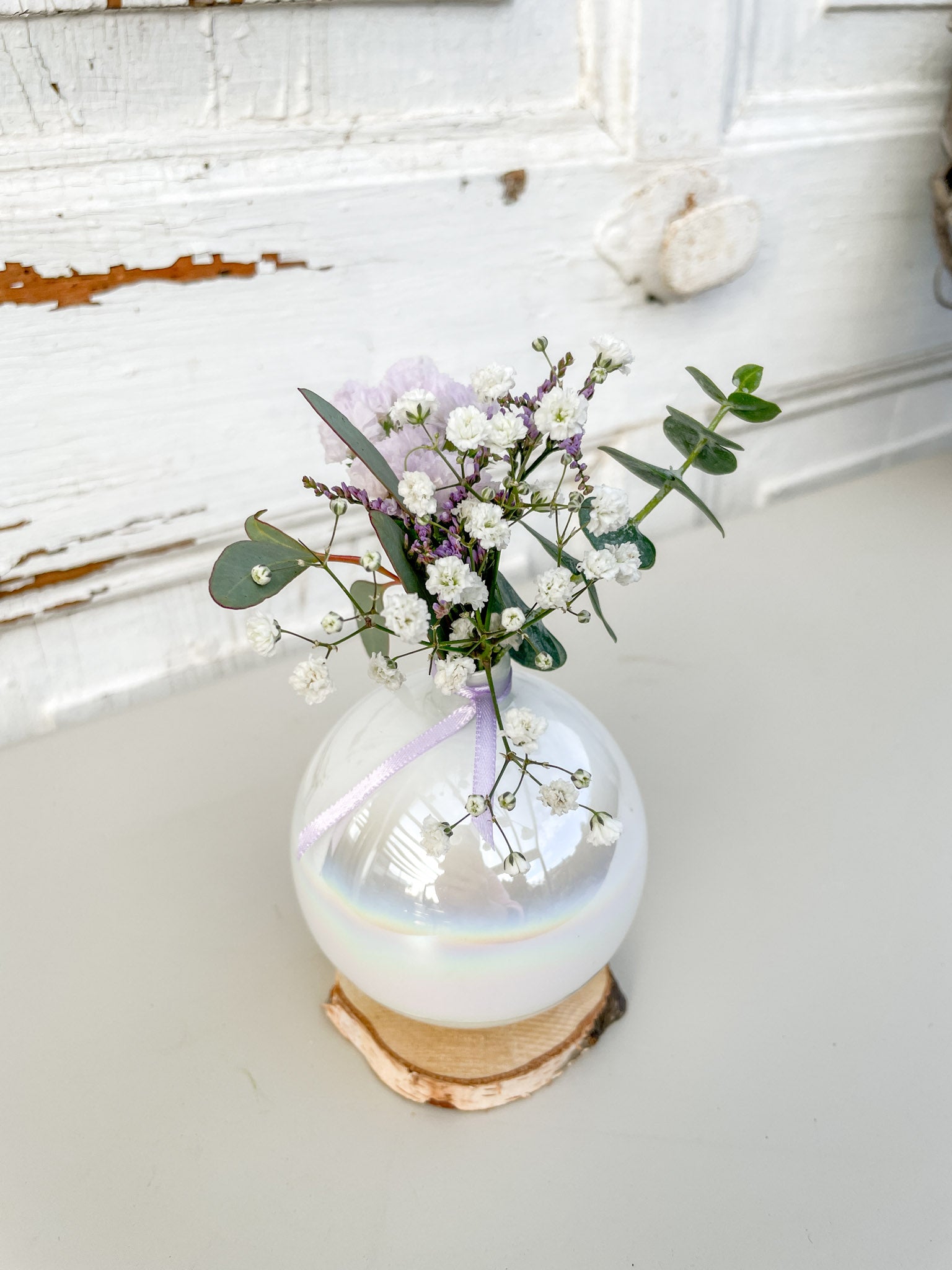 Detailaufnahme des Mini-Bouquets aus Eukalyptus, Strandflieder, Limonium, Statice in Lila und weißem Schleierkraut in der Christbaumkugel-Vase ‚Lila Blütenzauber