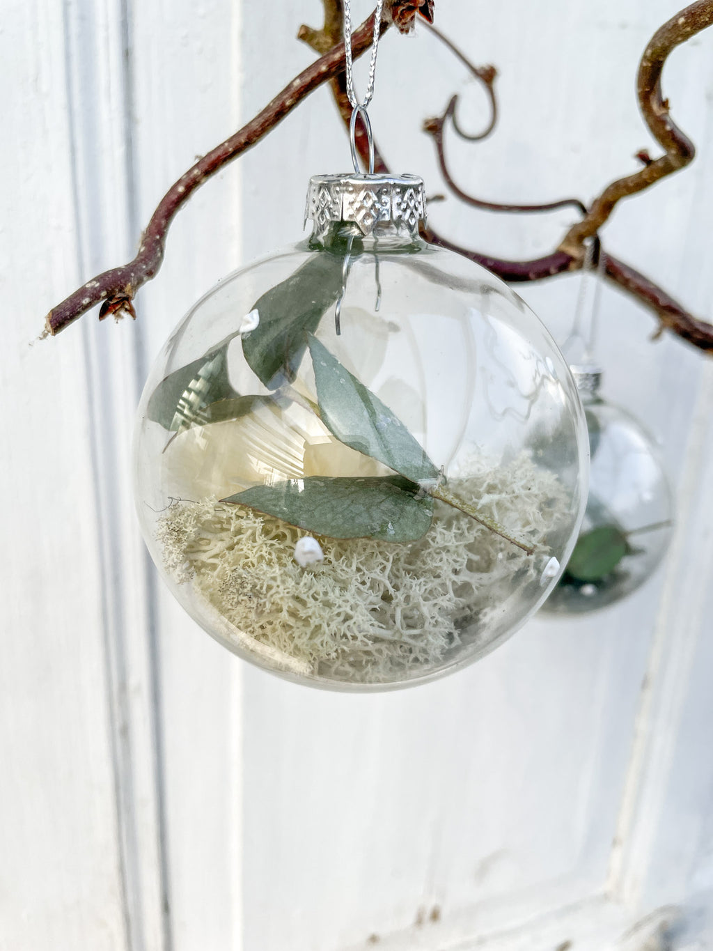 Glaskugel ‚Blütenzauber‘ Hochformat, transparent mit weißen Farbtupfen, gefüllt mit Islandmoos, Eukalyptus, Hortensien in weiß und Glitterstaub