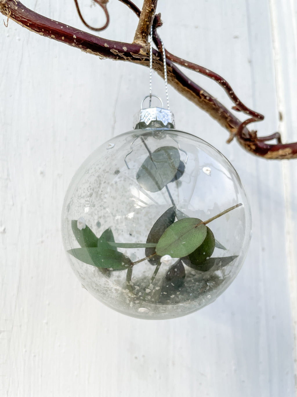 Glaskugel ‚Blütenzauber‘ Hochformat, transparent mit weißen Farbtupfen, gefüllt mit Eukalyptus und Glitterstaub