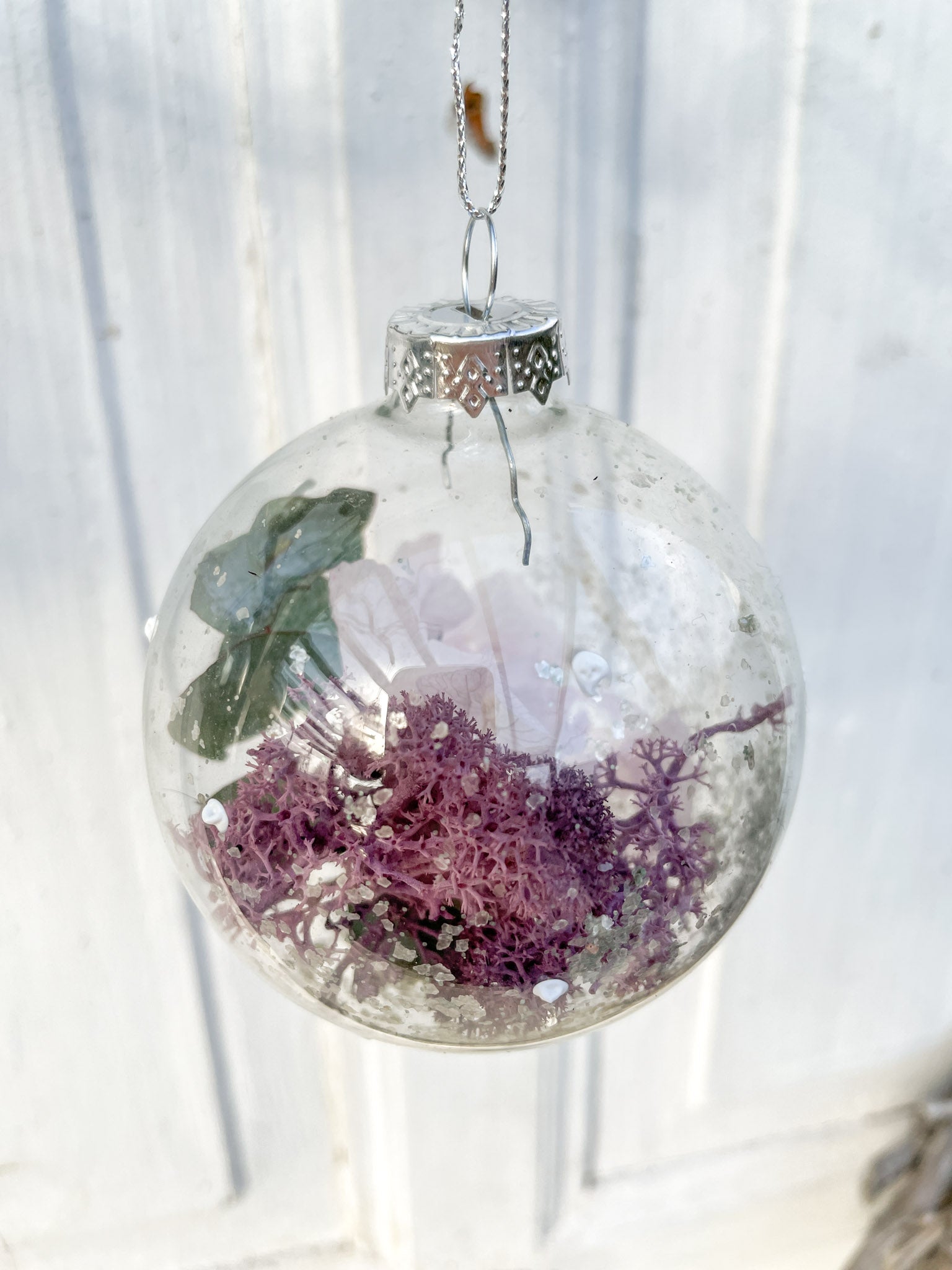 Glaskugel ‚Blütenzauber‘ Hochformat, transparent mit weißen Farbtupfen, gefüllt mit Islandmoos, Eukalyptus, Hortensien in Lila und Glitterstaub