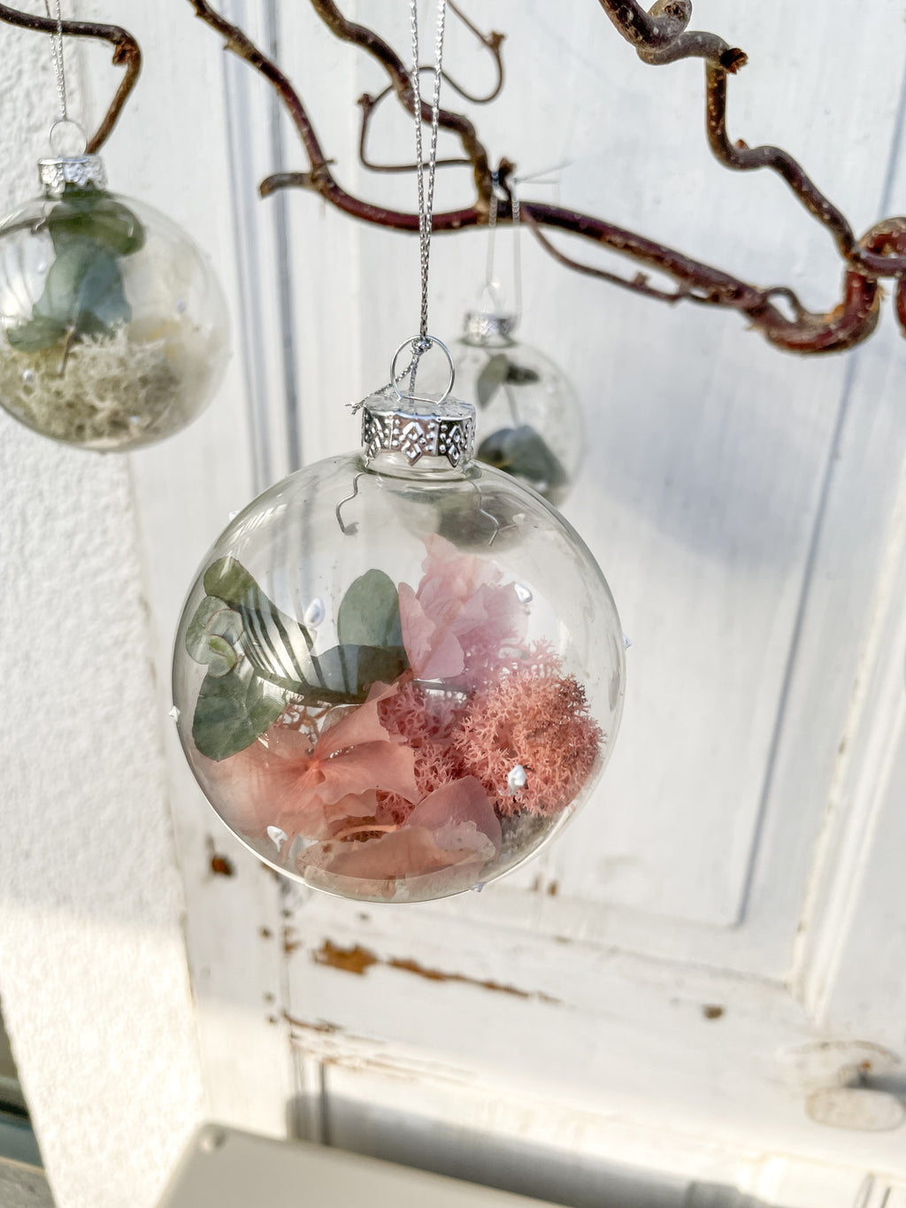 Glaskugel ‚Blütenzauber‘ Hochformat, transparent mit weißen Farbtupfen, gefüllt mit Islandmoos, Eukalyptus, Hortensien in Rosa/Lila und Glitterstaub