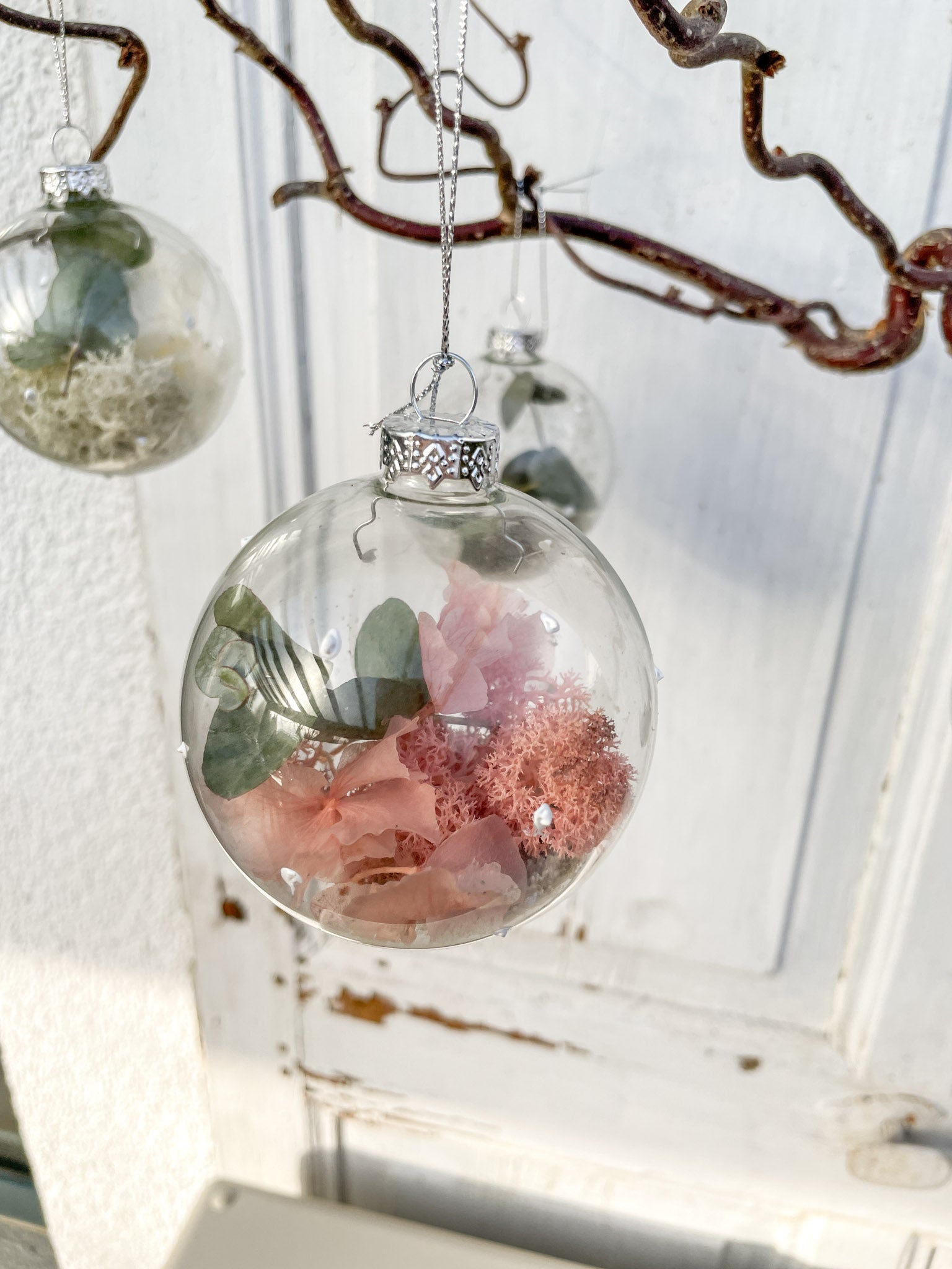 Glaskugel ‚Blütenzauber‘ Hochformat, transparent mit weißen Farbtupfen, gefüllt mit Islandmoos, Eukalyptus, Hortensien in Rosa/Lila und Glitterstaub