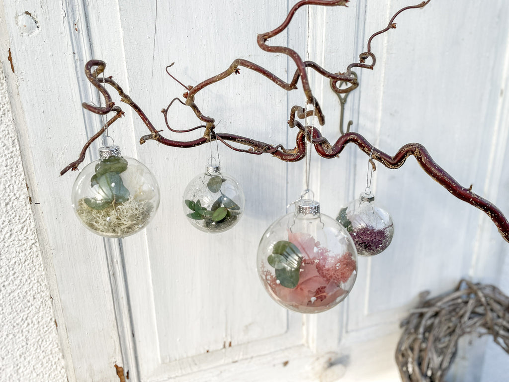 Glaskugel ‚Blütenzauber‘ Querformat, transparent mit weißen Farbtupfen, gefüllt mit Islandmoos, Eukalyptus, Hortensien in Rosa/Lila und Glitterstaub