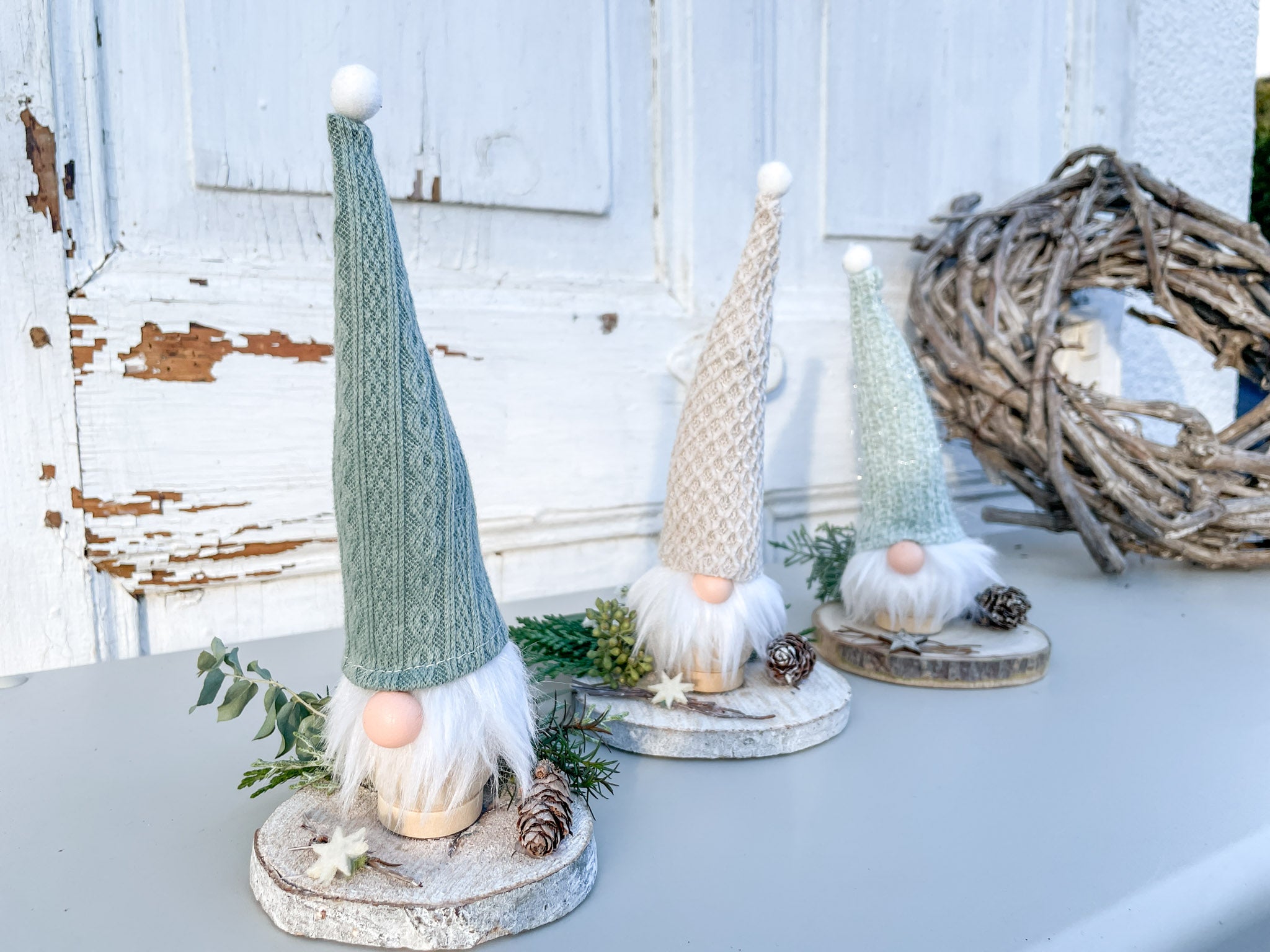 Kleiner Winterwichtel auf Holzscheibe, dekoriert mit Eukalyptus, Koniferengrün und Lerchenzapfen, handgemachte Winterdekoration aus Naturmaterialien