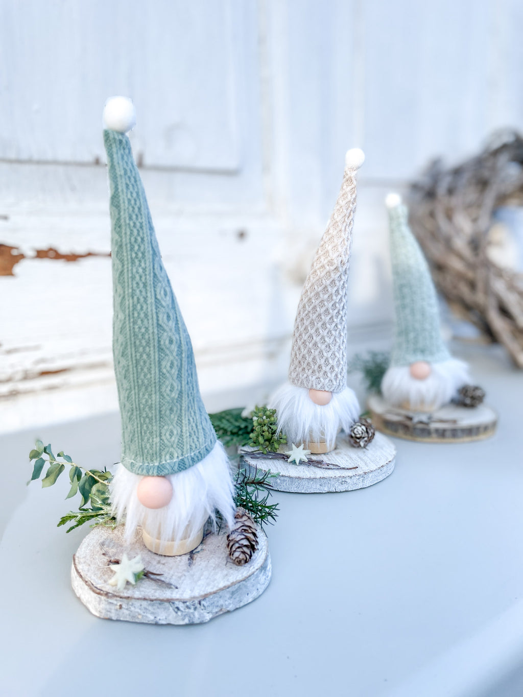 Kleiner Winterwichtel auf Holzscheibe, dekoriert mit Eukalyptus, Koniferengrün und Lerchenzapfen, handgemachte Winterdekoration aus Naturmaterialien