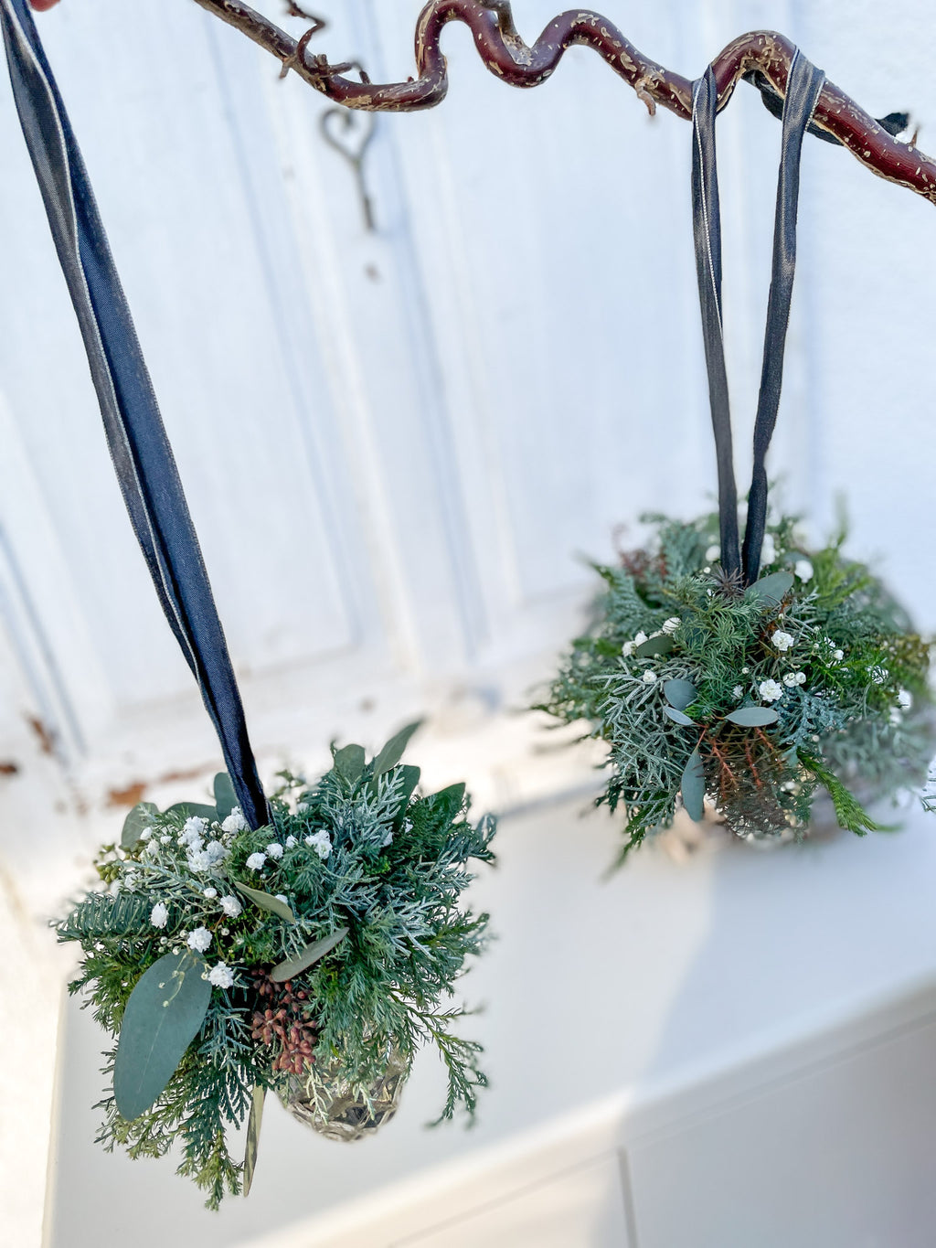 Ansicht von Oben des Mini-Bouquets aus Nadel- und Koniferengrün, Eukalyptus und weißem Schleierkraut auf Glaszapfen ‚Winter Elegance