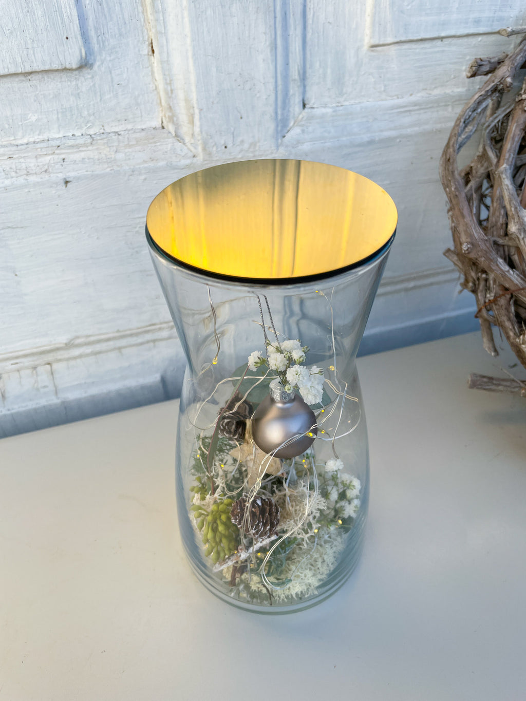 Nahaufnahme Glasvase Winterzauber, Nadelgrün, Eukalyptus, Zapfen, Islandmoss, goldener Deckel mit Anthrazit-Kugel, winterliche Tischdekoration