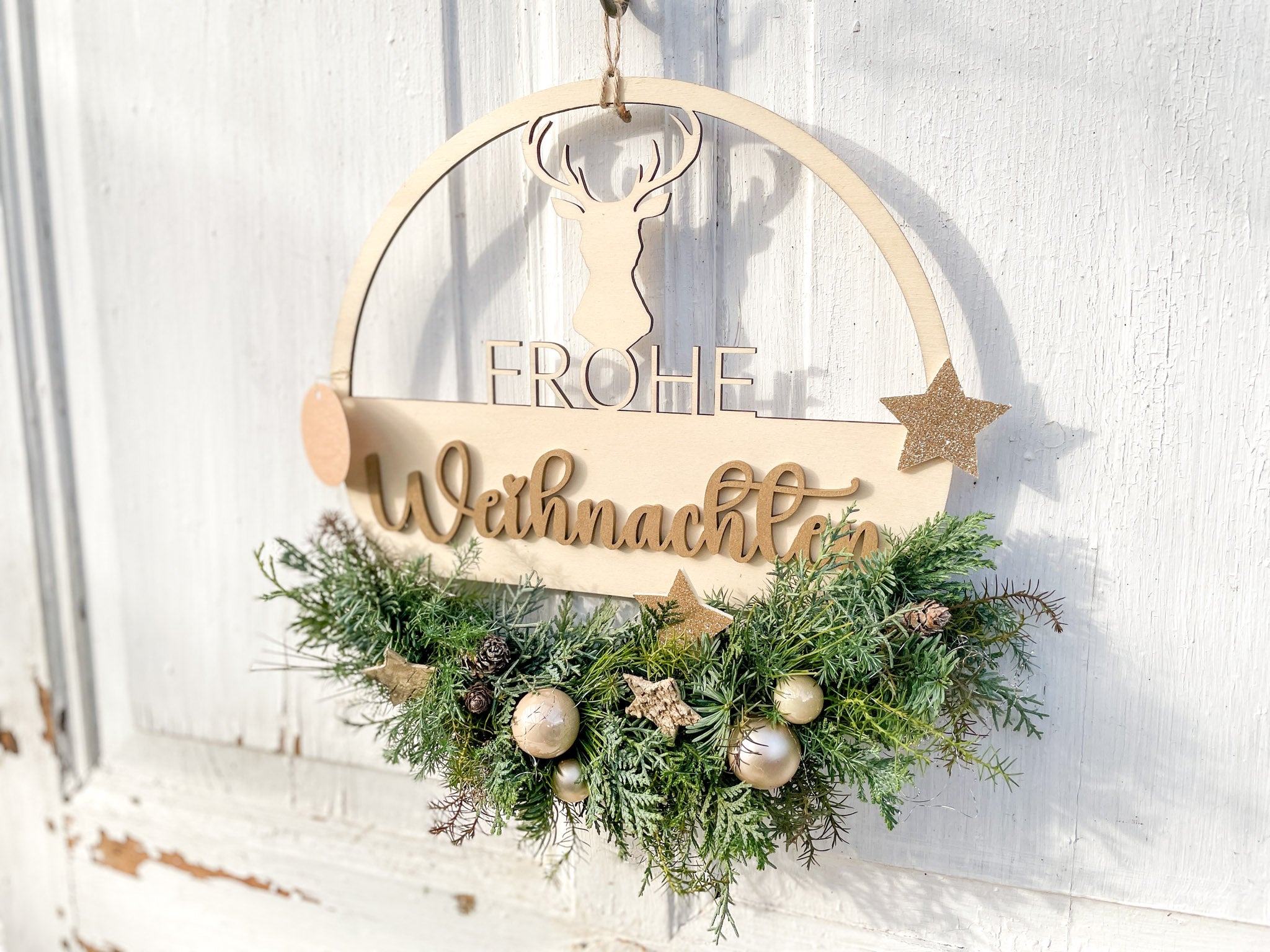Holzloop ‚Frohe Weihnachten‘ Querformat, filigraner Schriftzug mit Koniferengrün in Blau- und Grüntönen, Kugeln in Gold- und Cremetönen, Birkensterne und Lerchenzapfen