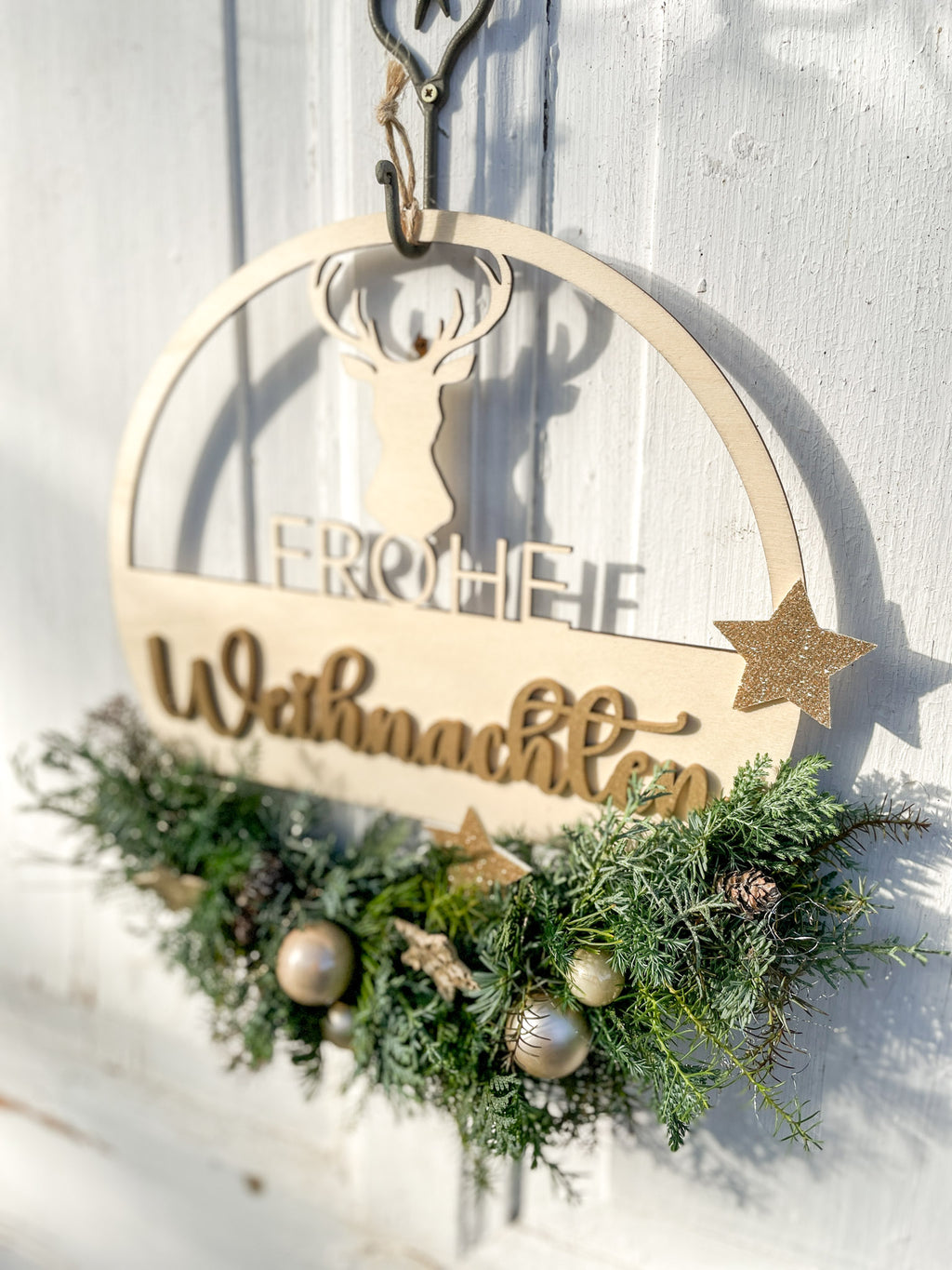 Holzloop ‚Frohe Weihnachten‘ Hochformat, filigraner Schriftzug mit Koniferengrün in Blau- und Grüntönen, Kugeln in Gold- und Cremetönen, Birkensterne und Lerchenzapfen