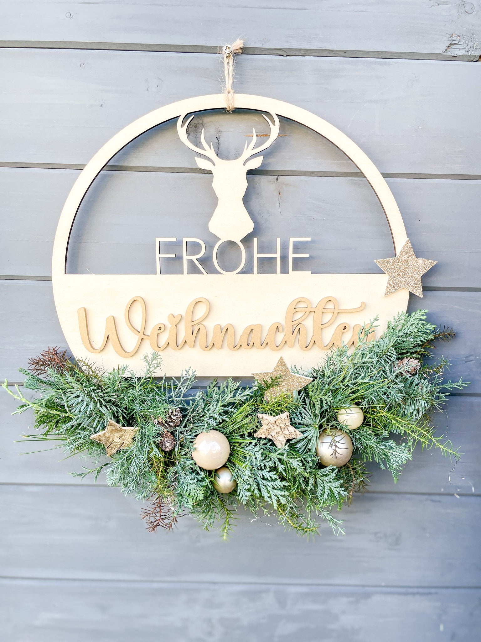 Holzloop ‚Frohe Weihnachten‘ Hochformat, filigraner Schriftzug mit Koniferengrün in Blau- und Grüntönen, Kugeln in Gold- und Cremetönen, Birkensterne und Lerchenzapfen