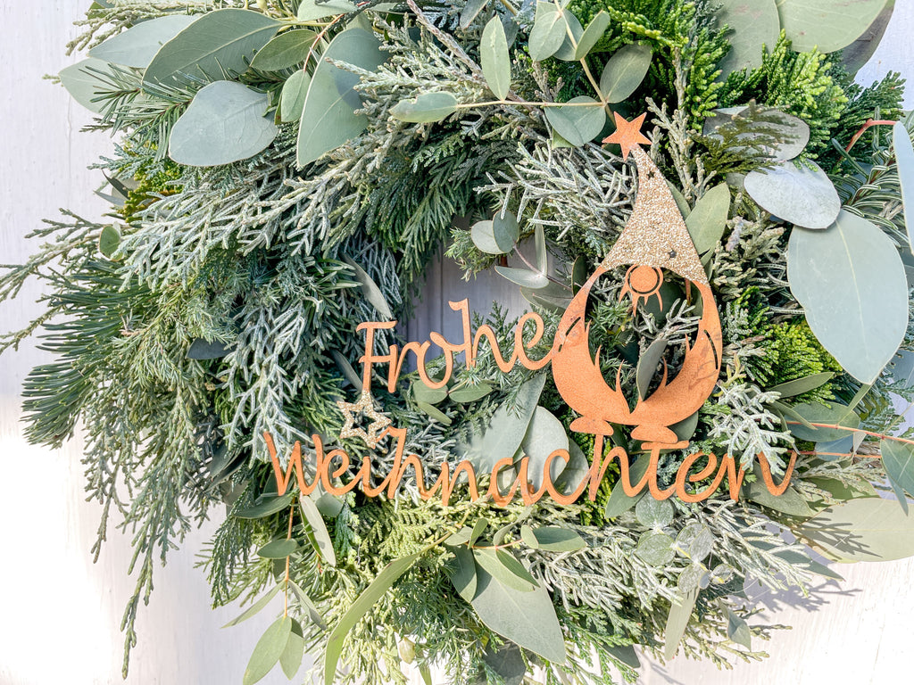 Nahaufnahme Winterkranz Frohe Weihnachten, Metall-Schriftzug, Winterwichtel, Goldglitzer-Details, winterliche Tisch- oder Türdekoration