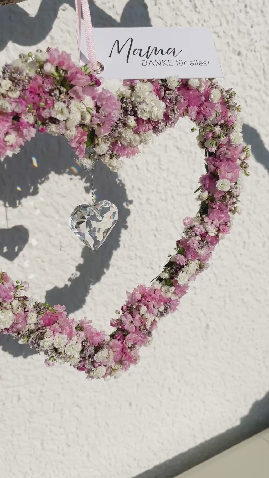 Video zeigt Handgefertigtes Draht Herz mit rosa Blüten und feinem Kristall Anhänger als Sonnenfänger