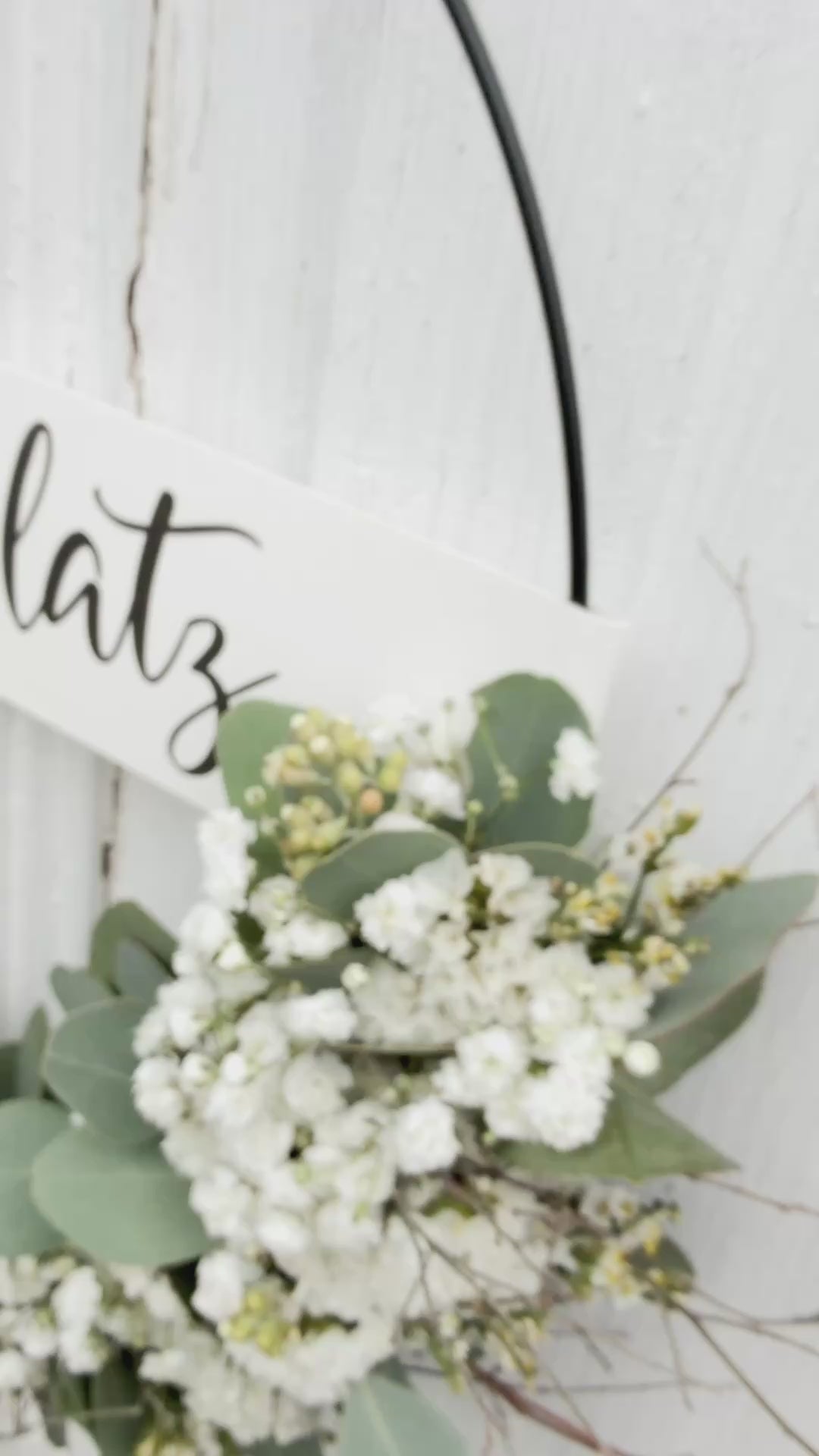Handgefertigter FlowerLoop „Lieblingsplatz“ mit weißen Blüten und Eukalyptus als Türdekoration an Holztüre.