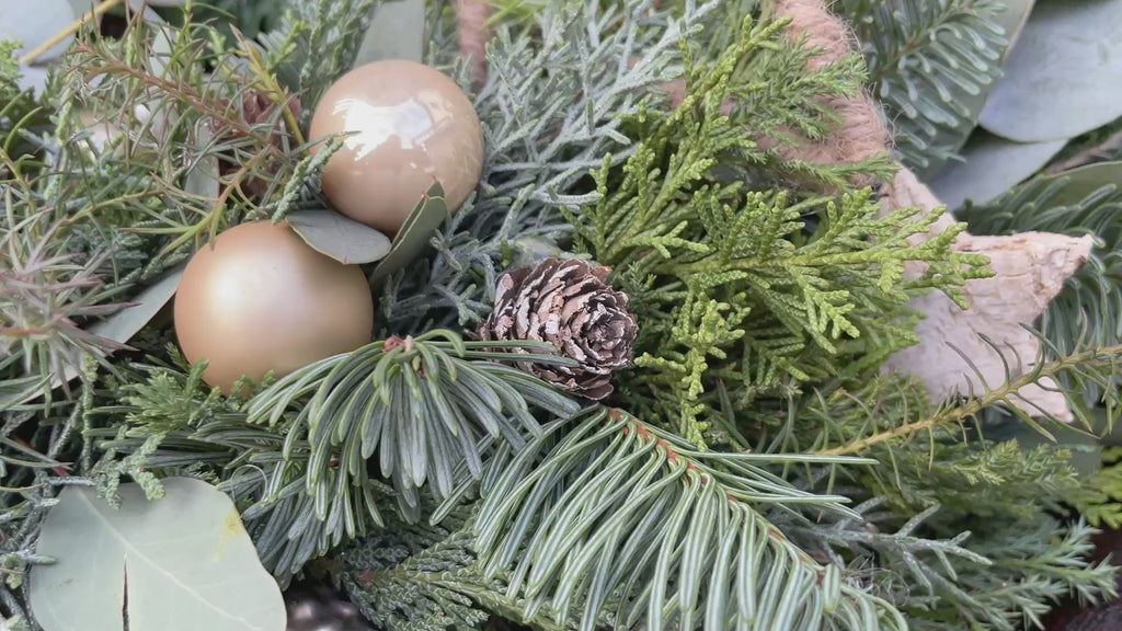 Video Querformat zeigt: Adventskranz Naturschimmer - natürliche Materialien u.a. Tanne, Eukalyptus, diverses Nadelgrün, optional: Sukkulente. Stumpenkerzen in hellbraun ergänzt um Dekokugeln in champagner-gold und ein farblich abgestimmtes Dekohighlight (tbd). 